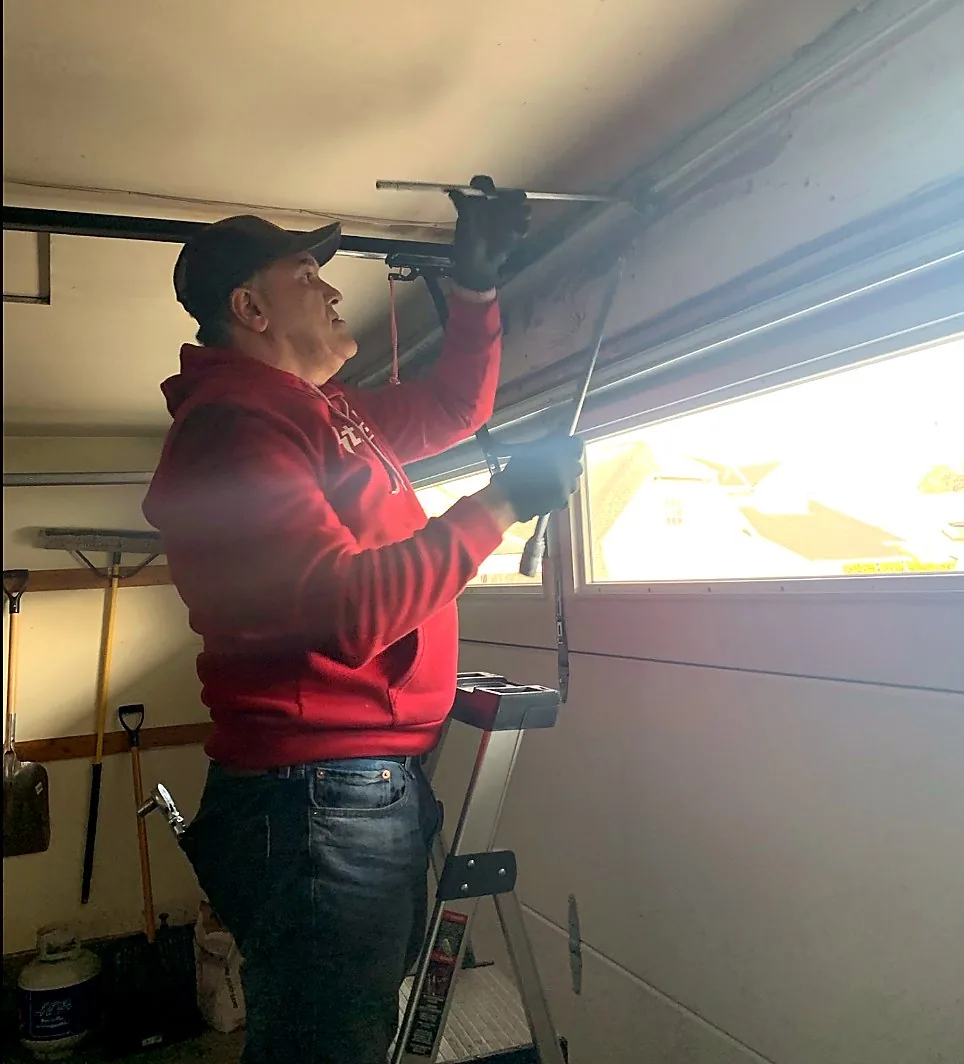 Technician adjusting a garage door track and roller
